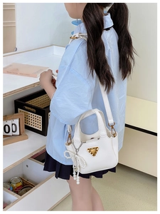 Dettaglio mini borsa bianca in pelle martellata con fiocco di perle e logo dorato