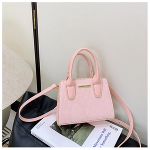 Close-up of pink snake-embossed shoulder bag with elegant gold hardware and silk scarf