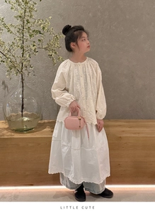 Détail d'un mini sac à bandoulière rose avec lettres embossées et pendentif pour enfants