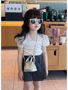 Détail d'un mini sac bandoulière en paille avec bordure argentée pour tenue d'été enfant