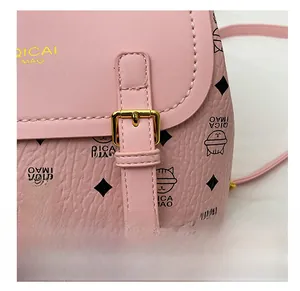 Detail of pink pebbled leather bag featuring cat pattern and gold metal buckle strap