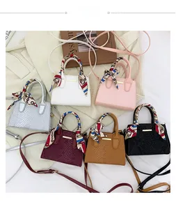 Flat lay of small embossed shoulder bags in six colors with silk scarves on handles