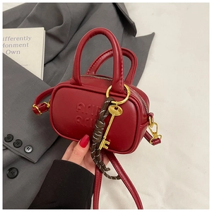 Détail du mini sac en cuir rouge avec lettres embossées et pendentif clé dorée