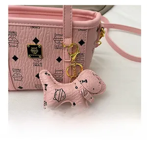 Detail einer rosa Handtasche aus Leder mit niedlichem Hundeanhänger und goldener Hardware