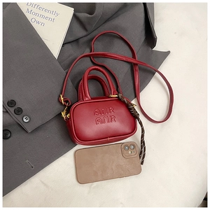 Mini sac rouge bandoulière avec gaufrage Arir et breloque tissée par rapport à un smartphone