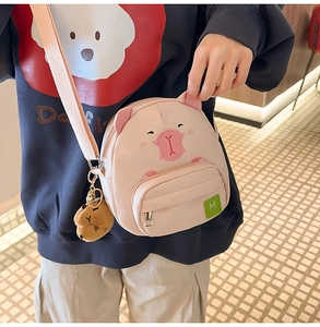 Détail du sac bandoulière cochon rose avec pendentif ours en peluche et broderie