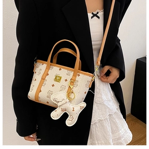 Detailansicht der bedruckten Beuteltasche mit Katzenmuster, Gurt und Anhänger am Model