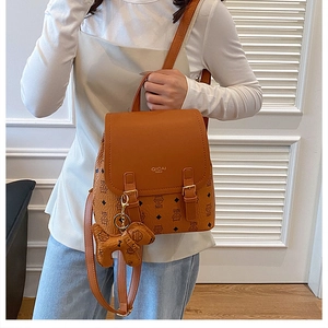 Detail of brown PU leather backpack featuring brand monogram print and cute dog charm