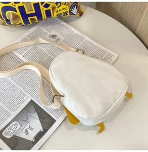 Detail of cute canvas small crossbody bag with funny duck design on newspaper background