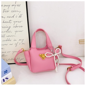 Dettaglio mini borsa rosa in finta pelle con ciondolo a fiocco e placca triangolare