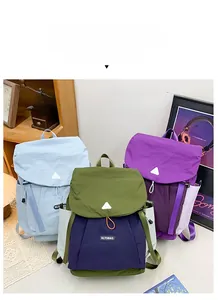 Three children's nylon backpacks in light blue, purple, and green on a wooden shelf