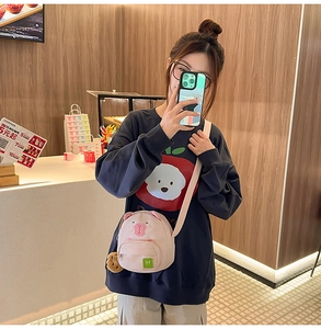 Détail du sac à bandoulière cochon rose avec logo M et charmant petit biscuit