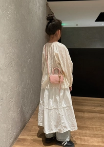 Détail latéral d'un mini sac bandoulière en cuir rose avec logo embossé et détails dorés