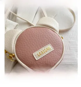 Close-up of pink and white round shoulder bag featuring cute 3D bear ears and PU leather texture