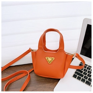 Dettaglio di una borsa mini arancione vivace con placchetta metallica dorata triangolare