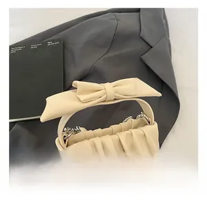 Detail of cream white pleated handbag featuring a large bow handle and silver hardware