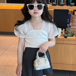 Ensemble mode enfant avec haut à manches bouffantes, jupe noire et petit sac argent