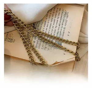 Close-up of vintage gold metal chain strap on old book pages for kids handbag accessory