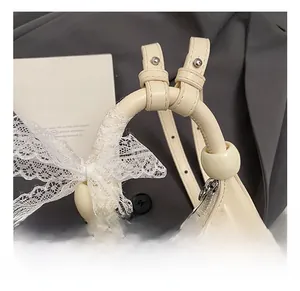 Détail du sac croissant en cuir crème avec nœud en dentelle et fermeture éclair argent