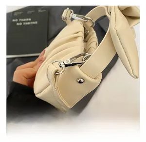 Detail shot of the beige pleated bag with premium silver metal hooks and bow handle