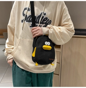 Detailed view of black canvas cartoon duck crossbody bag with 3D yellow beak and feet