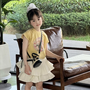 Fillette en t-shirt chat jaune et jupe à volants avec un mini sac bandoulière en paille