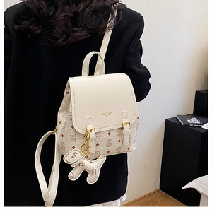 Detail of cream mini backpack with puppy charm and metallic buckle on model