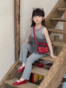 Close-up of a child's red square crossbody bag with bow detail and ballet flat shoes