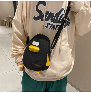 Detail of black canvas duck crossbody bag showing 3D yellow beak and adjustable strap