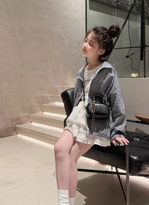 Fillette avec mini sac bandoulière en cuir noir à lettres embossées et jupe en dentelle