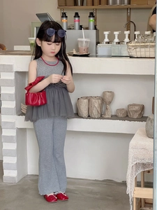 Detailed view of girls' grey ruffled sleeveless top and flared trousers with red accessories