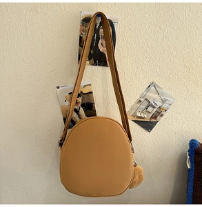 Détail du sac bandoulière rond Capybara avec pompon en peluche et large sangle en toile