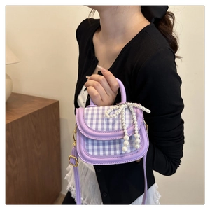 Detail of lavender plaid handbag featuring a woven pearl bow and top handle strap