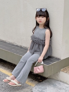 Détail d'un sac à main cœur avec perles porté par une fille en tenue grise chic