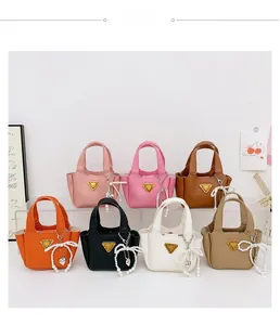 Dettaglio delle mini borse tote con fiocchi di perle e placche logo triangolari in metallo
