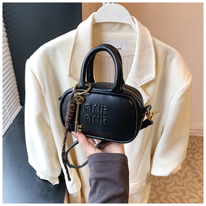 Détail du mini sac en cuir grainé noir avec lettres embossées et breloque clé dorée