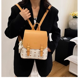 Detail of mini backpack showing orange leather flap and beige monogram print with coin purse