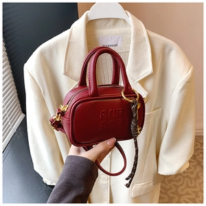 Vue détaillée du mini sac en cuir bordeaux avec lettres embossées et breloque anneau