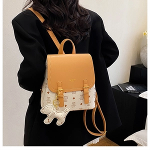 Detail of mini backpack with brown leather flap and cute white puppy keychain charm