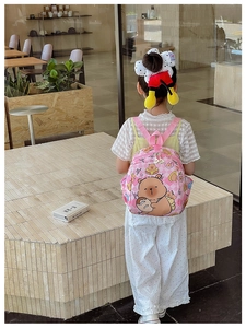 Pink cartoon bear backpack for kids shown in a lifestyle setting with cute accessories