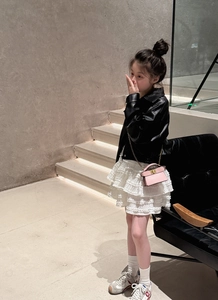 Detail view of pink mini chain bag paired with black leather jacket and lace skirt