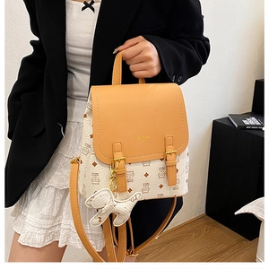Detail of the yellow and cream backpack with cat prints and a cute dog charm accessory