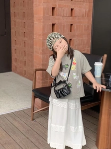 Girl's stylish outfit featuring a black pleated crossbody bag and a woven grid sun hat