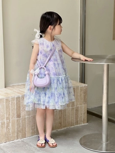 Détail d'un sac à main croissant violet avec robe en dentelle florale assortie et nœud à cheveux