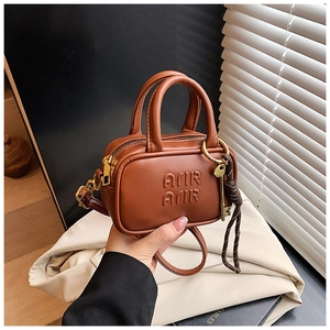 Détail d'un mini sac à main marron avec lettrage AMIR AMIR et pendentif clé