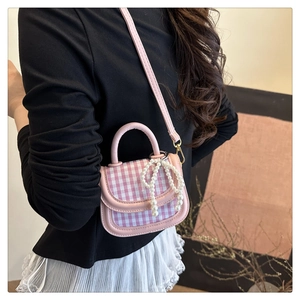 Pink checkered mini bag with pearl bow detail worn by a model in a lifestyle setting