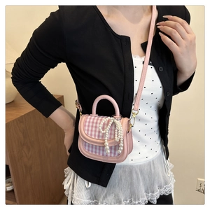 Detailed view of sweet mini plaid handbag with pearl bow pendant and pink strap