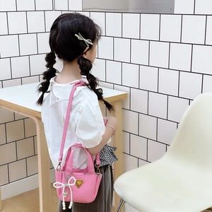 Mini borsa rosa da bambina con ciondolo a fiocco di perle e decoro a triangolo dorato
