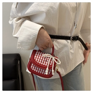 Detail of red and white plaid mini handbag with pearl bow pendant and leather strap