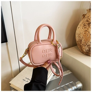 Mini sac à bandoulière rose avec lettres gaufrées présenté dans un cadre lifestyle élégant